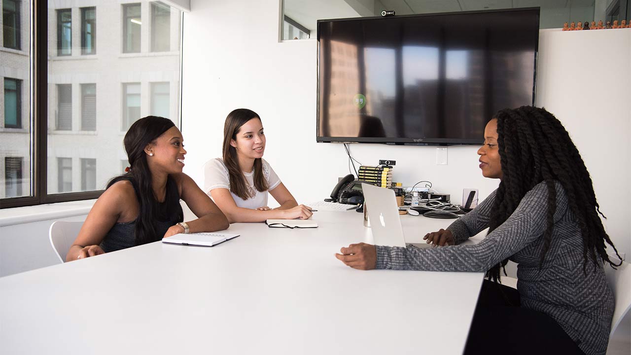 three woman talking in a work meeting, around a table