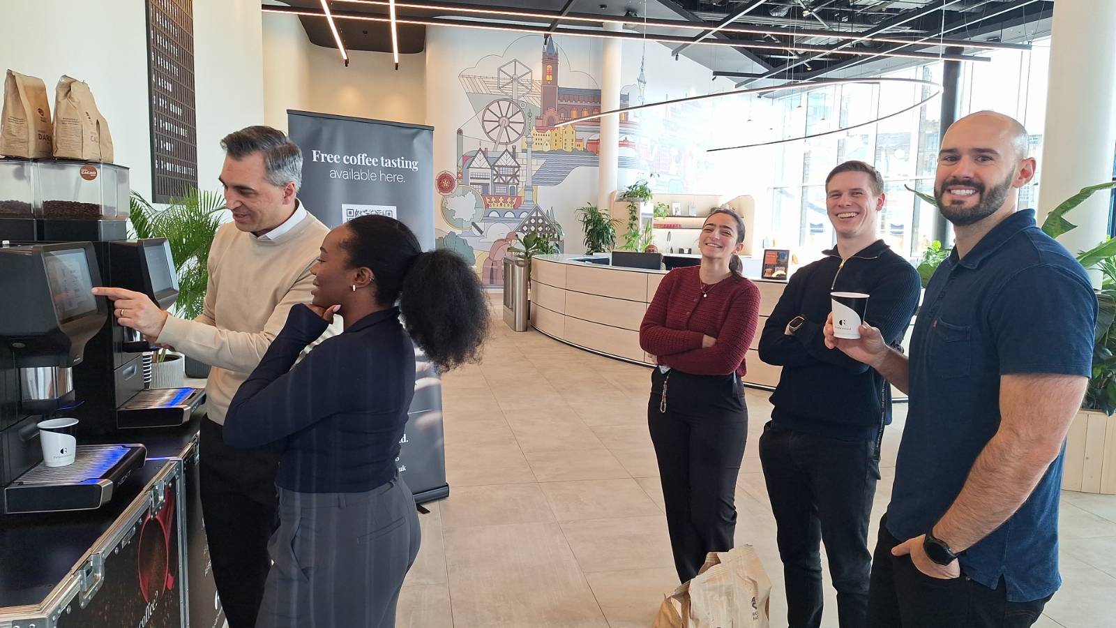 people stanbding around coffee machine, laughing