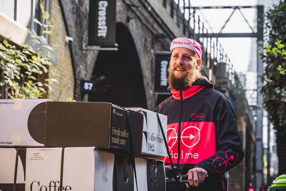 PedalMe driver standing next to bike loaded with FreshGround Coffee