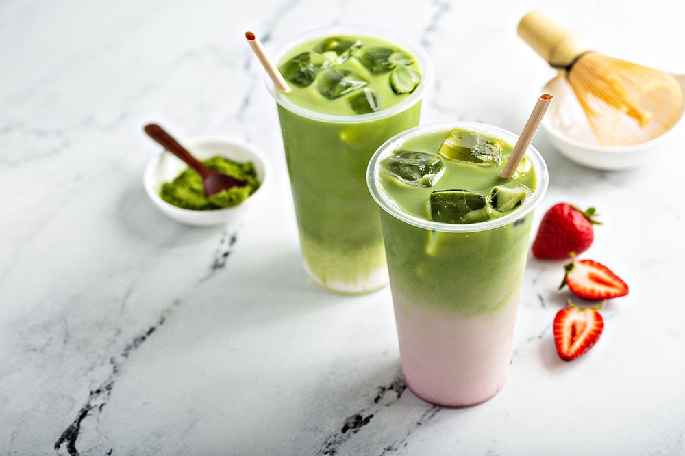 Two cups of iced matcha, both very trending drinks, one plain and one with strawberry.